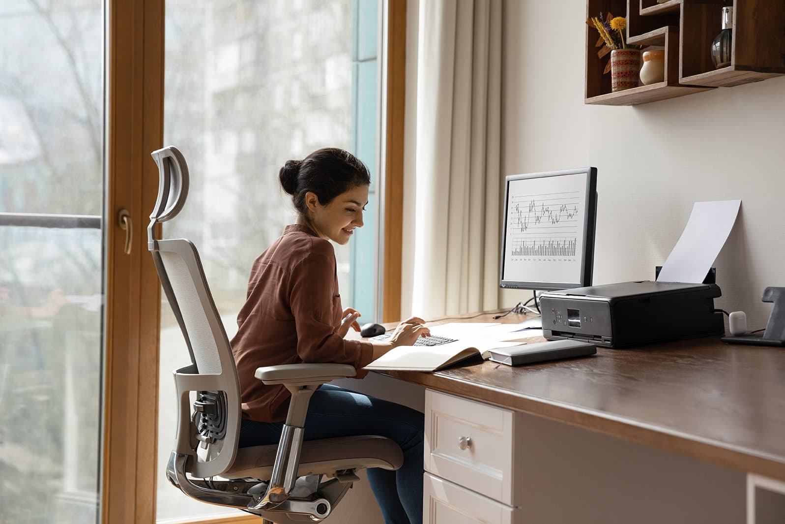 Concentrated young woman studying or working on computer in modern home office. Remote work concept.