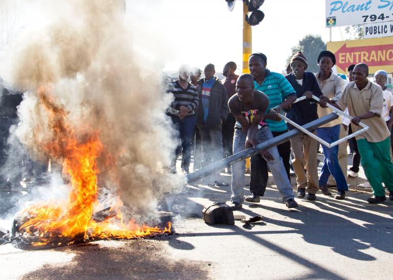Des participants aux troubles civils dans une province affectée d'Afrique du Sud alimentent un feu au milieu d'une rue.