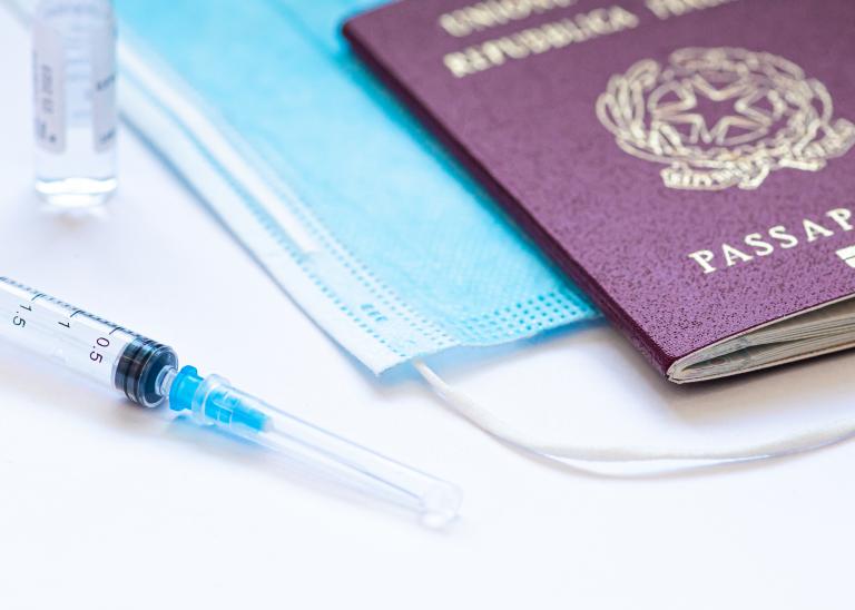  Syringe with needle, vial, face mask, and passport on white table ready to be used. 