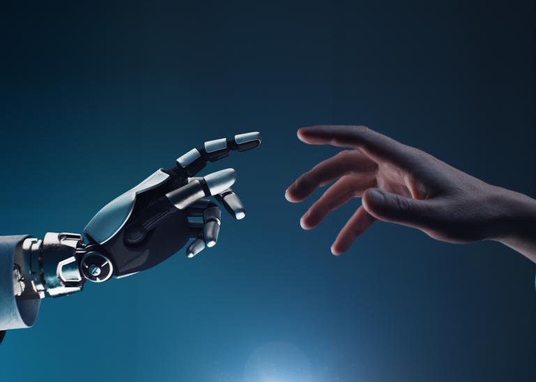 Robotic hand and human hand with fingers outstretched reaching towards one another against a blue background.