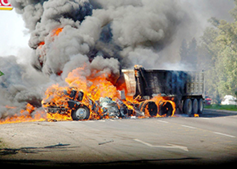 A burned vehicle is used as a roadblock by drug traffickers.