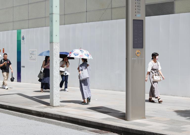 People passing on the street in Tokyo during a heatwave.