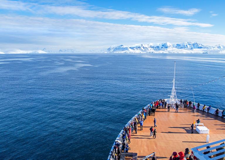 View from the deck of a cruise ship sailing in a vast expanse of ocean blue.