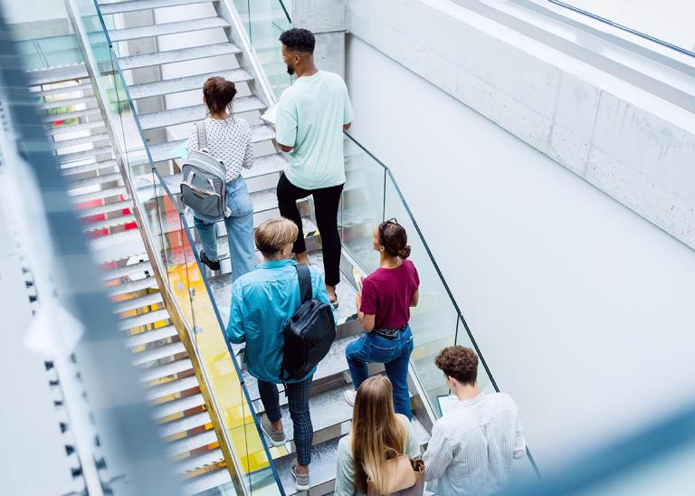 university students walking up a staircase in a building