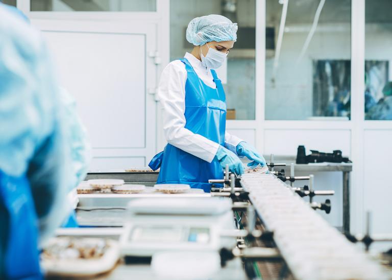 food manufacturer woman wearing protective gear handling food in a warehouse