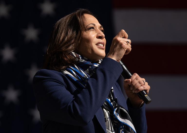 Presidential Candidate Vice-President Kamala Harris speaking at an event with the background of the US flag.