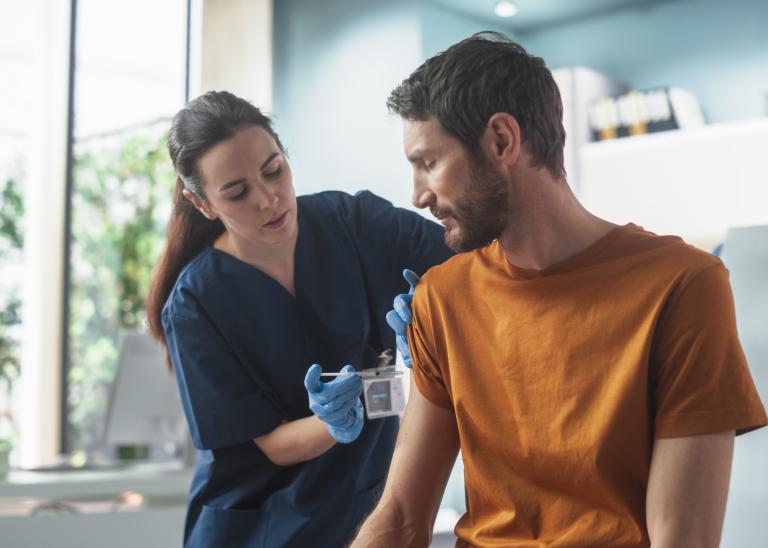 nurse administering a vaccine to a male patient in a clinical setting