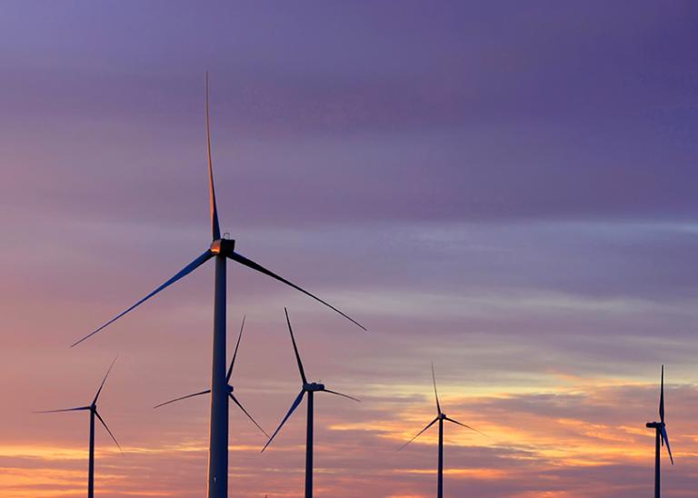 wind turbines silhouetted against a sunset or sunrise