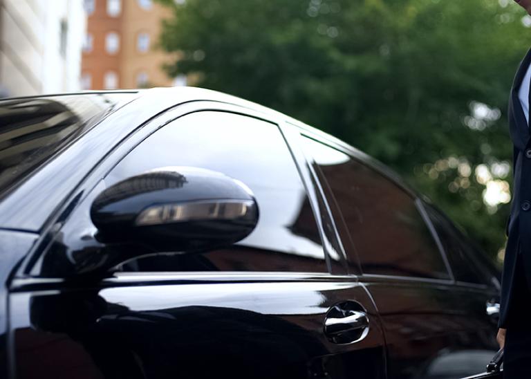 executive protection concept man standing by a black car