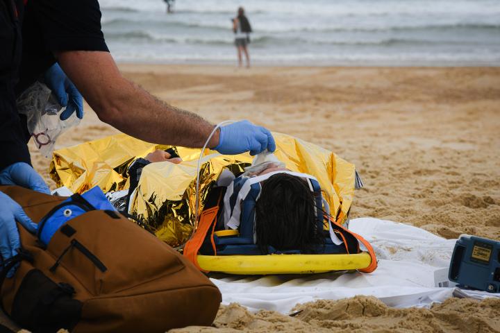 a patient on a stretcher receiving medical treatment with oxygen at the beach